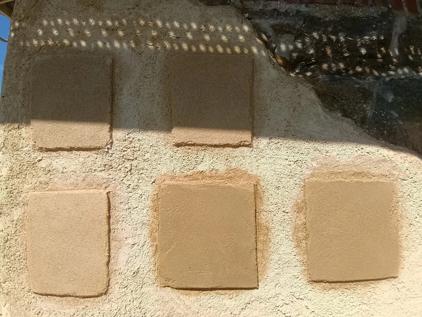 Échantillons d'enduits à la chaux teintés sur un mur